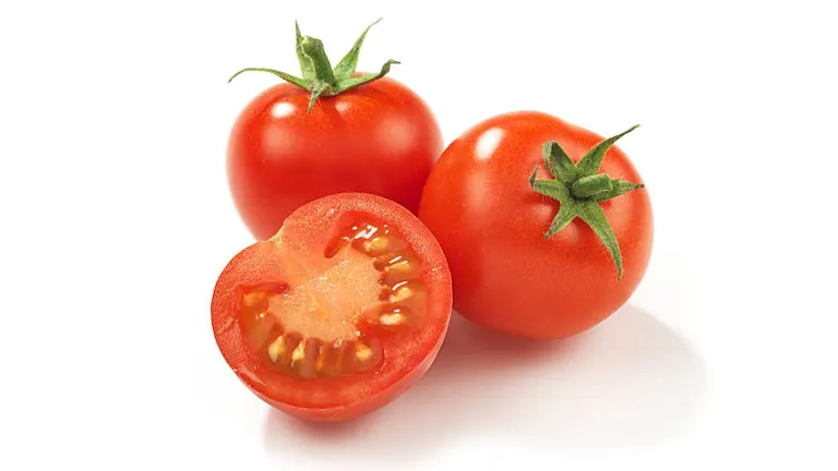 Three ripe red tomatoes, with one cut in half to reveal the juicy interior, displayed on a white background.