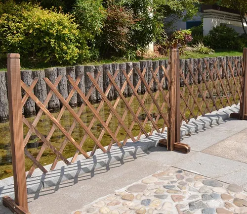 Expandable wooden lattice trellis set up along a pathway in a garden, enhancing the border with its criss-cross pattern.