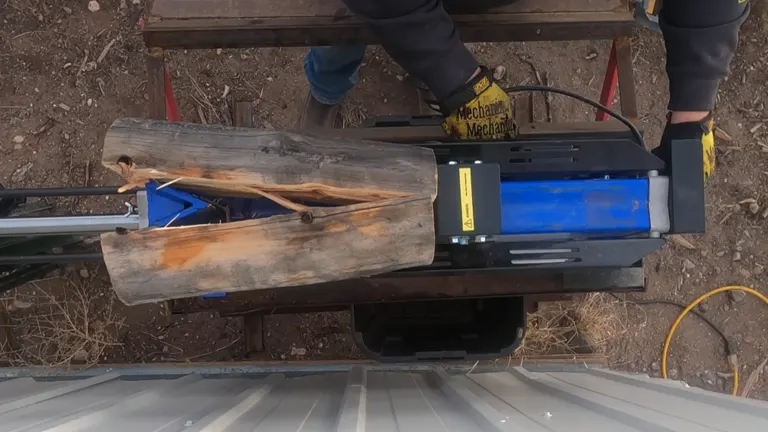 Top view of a log being split by a Bilt Hard electric log splitter on a metal table.
