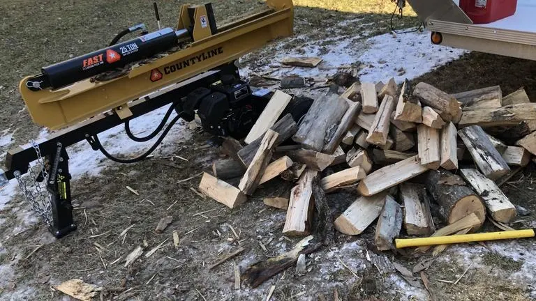 CountyLine 25-Ton Log Splitter next to a pile of split firewood in snow.