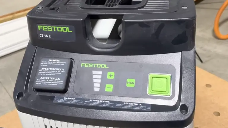 Close-up of the control panel on the Festool CT 15 E Dust Extractor, featuring green operational buttons, warning labels, and the Festool logo on a dark gray surface.