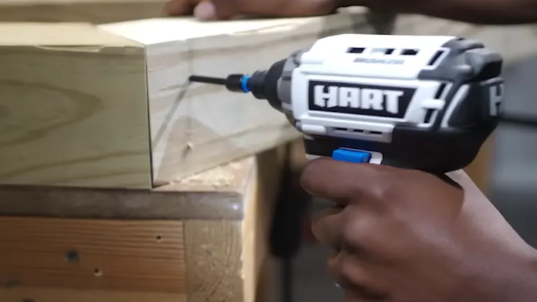 Close-up of a HART 20V impact driver screwing into a wooden corner joint.