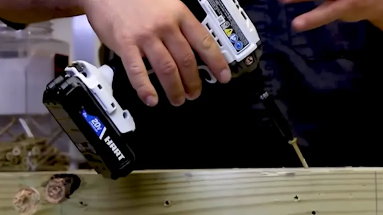 Person holding a HART 20V impact driver, adjusting the bit on a workbench.