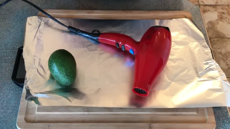Green avocado and a blower on top of foil, with a chopping board underneath.