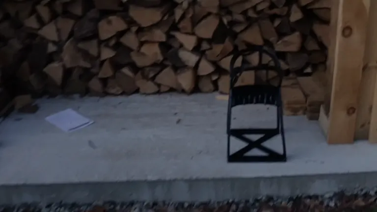 Kabin Kindle Quick Log Splitter positioned on a concrete slab in front of a woodpile, ready for use.