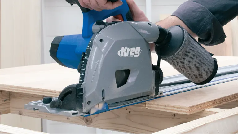 Person using a Kreg track saw to make a precise cut on a piece of plywood, with the track guiding the saw for an accurate cut.