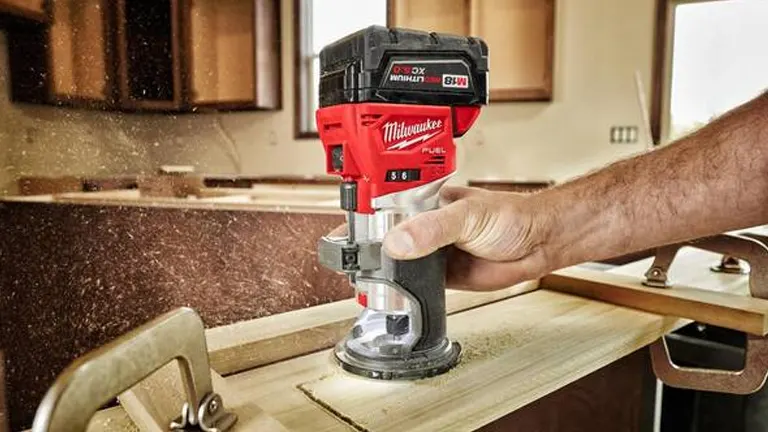 A Milwaukee compact trim router in use, rounding over the edge of a wooden board, with sawdust being collected efficiently.