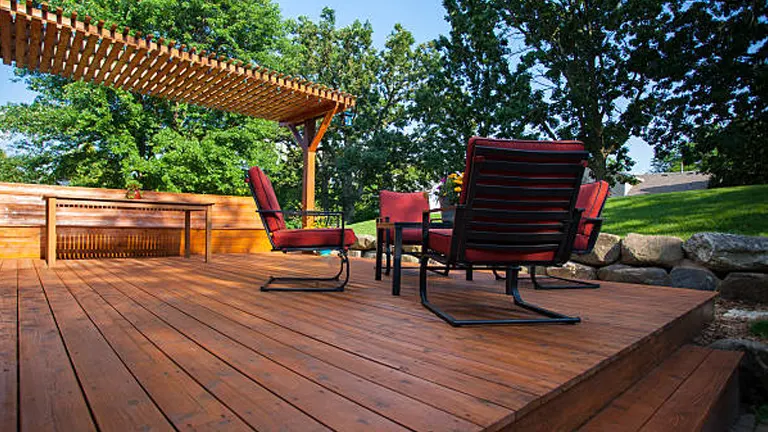 An outdoor wooden deck with a pergola and red patio furniture, illustrating the use of wood in outdoor projects.