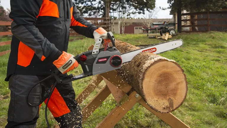 Worker cutting a large log using an Oregon electric chainsaw on a sawhorse.