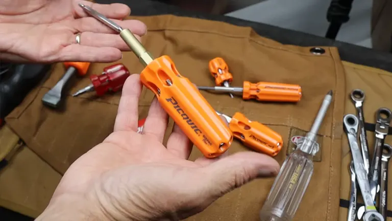 A person lifting a Picquic Screwdriver, with many tools positioned underneath it
