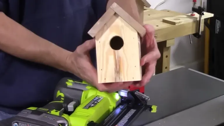 Completed birdhouse project next to the Ryobi P320 Airstrike Brad Nailer on a workbench.