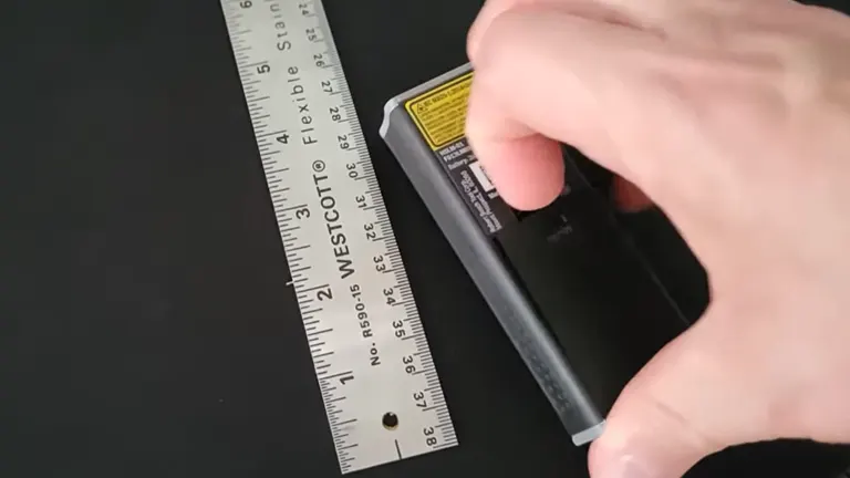 Close-up of a hand inserting batteries into the Dremel 3-in-1 Digital Measurement Tool, highlighting the easy-access battery compartment.