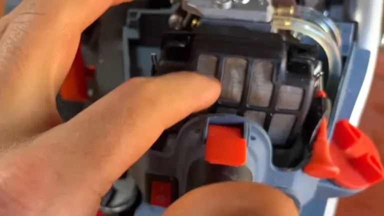 Close-up of a person's hand adjusting the air filter on a Senix chainsaw.