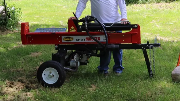 Person operating a red SpeeCo SplitMaster 22-ton log splitter on grass.