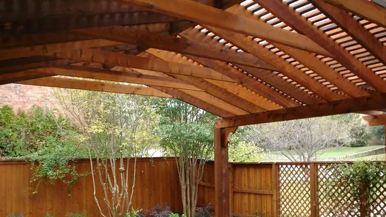 Wooden pergola with lattice design overlooking a backyard.