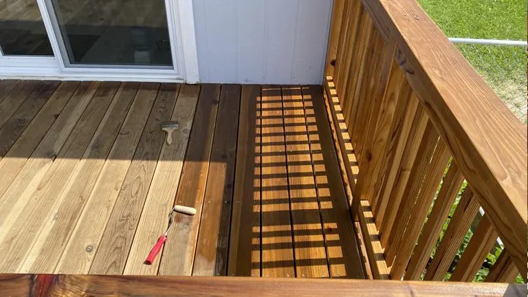 Staining a deck with a brush next to a sliding door.