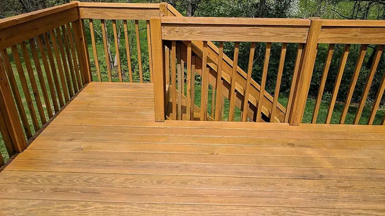 Finished wooden deck with railing in a backyard.