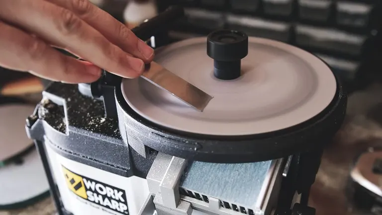 Close-up of the Worksharp tool sharpener in action, with a chisel being sharpened on the rotating disc, showing its precision sharpening capabilities.