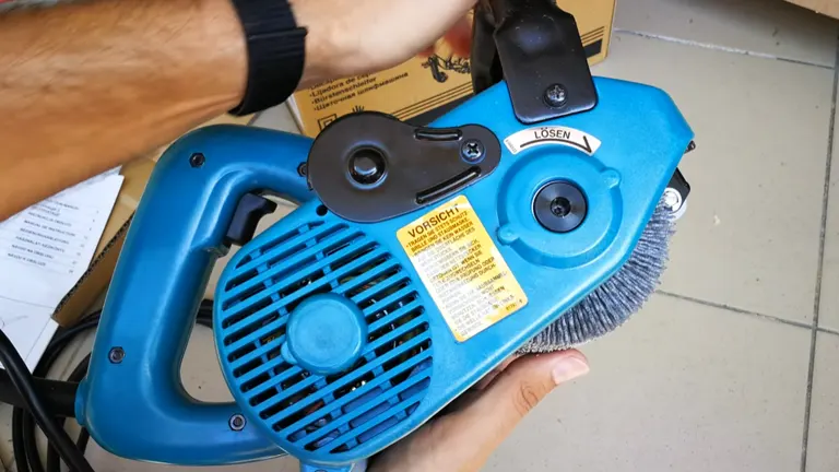 Hand holding a Makita 9741 Wheel Sander showing its underside and adjustment mechanisms.