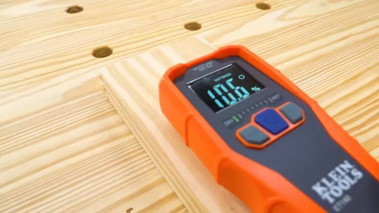 A digital moisture meter reading 10.5% placed on a piece of light-colored wood with a grain pattern, used to measure the wood's moisture content.