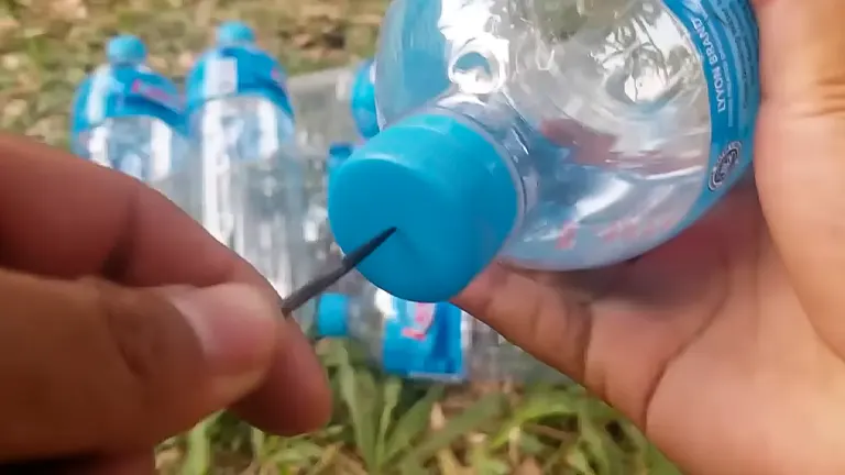 Process of puncturing a blue cap on a clear water bottle with a needle to create a drip irrigation system.
