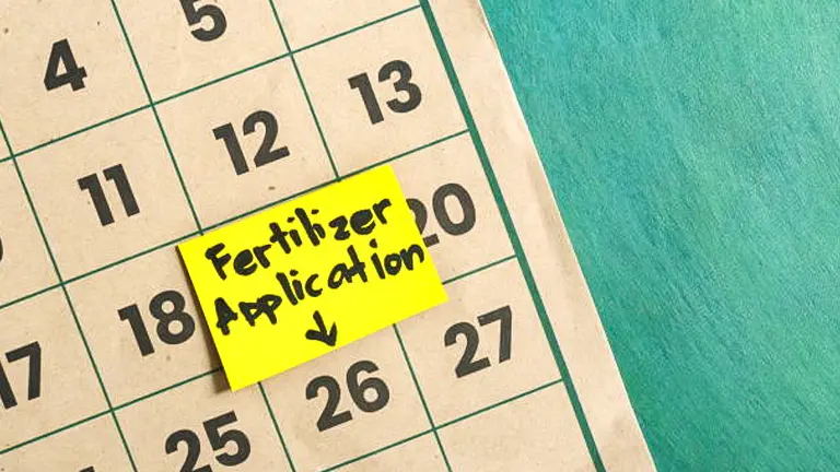 A calendar with a yellow sticky note marking 'Fertilizer Application' on a specific date.