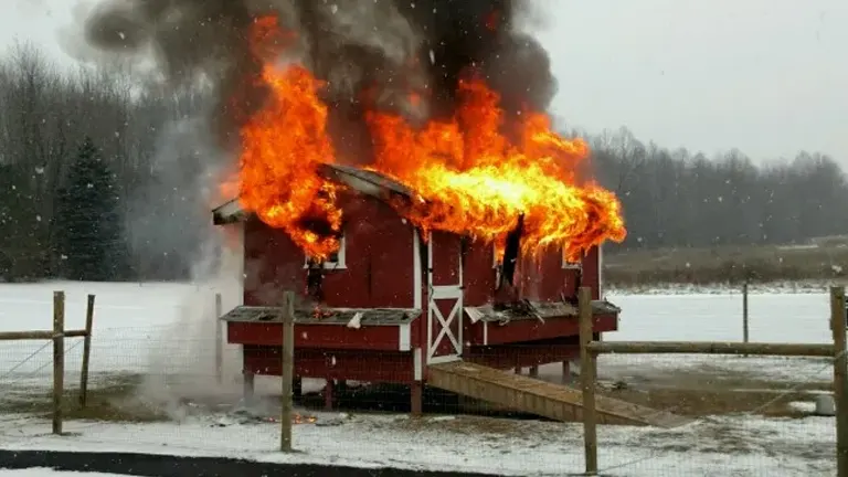 A henhouse engulfed in flames against a snowy backdrop.