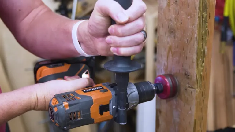Man using an orange cordless drill to bore into a wooden post.
