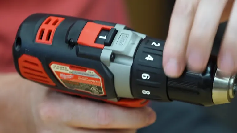 Close-up of an orange cordless drill's adjustable chuck showing settings.
