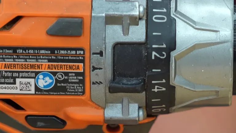 Detailed view of the numerical settings on the chuck of an orange and black cordless drill, focusing on the adjustment collar.