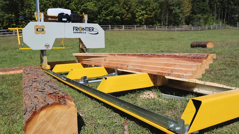 A Frontier Sawmill OS27 processing a large log outdoors, showcasing its sturdy frame and vibrant yellow components.