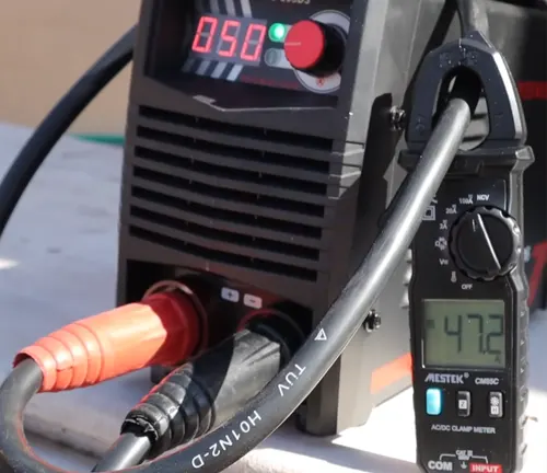 AC/DC clamp meter connected to a welding machine with a voltage reading shown.

