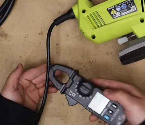 Using a clamp meter to measure electrical current flowing through a cable.
