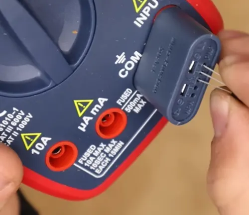 Close-up of a multimeter's probe inserting into a measurement jack.
