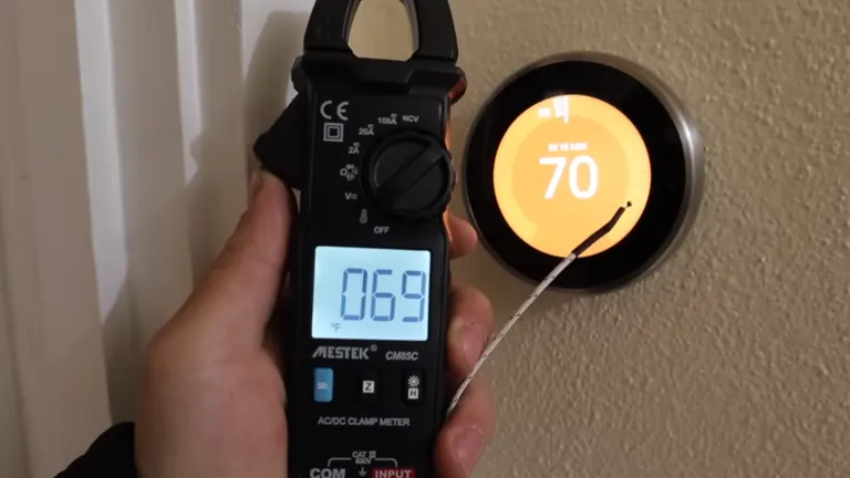Image of an AC/DC clamp meter displaying a reading against a thermostat.
