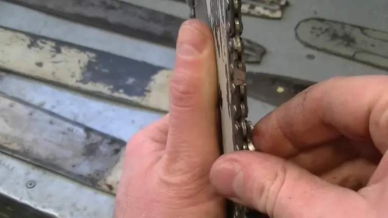 Close-up image of a chainsaw chain, showing significant wear and damage to the drive links.

