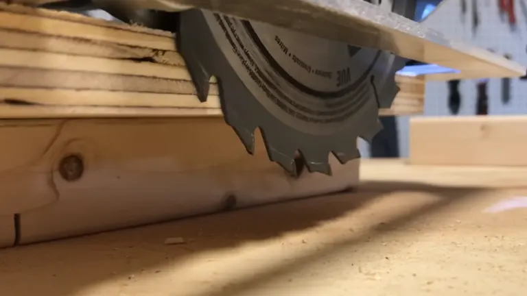 Close-up view of a circular saw blade cutting through a stack of wooden planks.