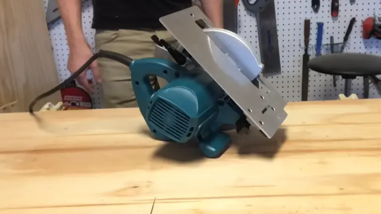 Circular saw placed on its side on a workbench, with focus on its handle and controls.
