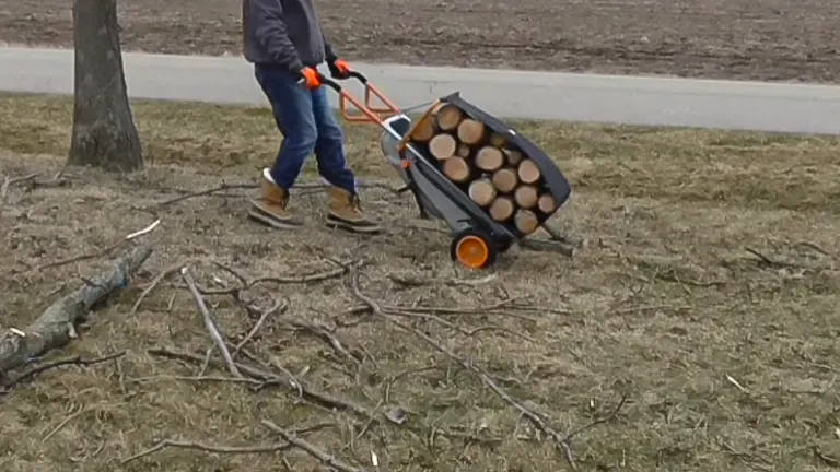 Man hauling a load of firewood with a WORX Aerocart on a grassy field.