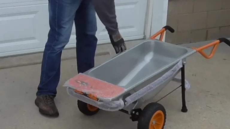 Man unboxing a WORX Aerocart from a cardboard box in a driveway.