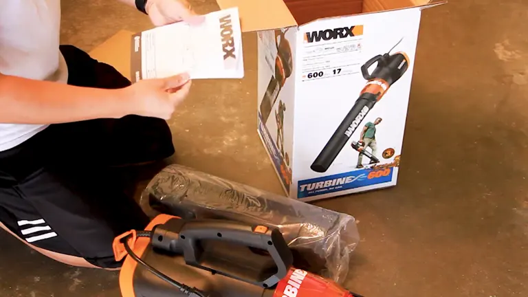 Unboxing of the Worx Turbine 600 electric leaf blower with components laid out next to the box on a garage floor.