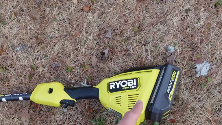 Ryobi gutter cleaner attachment and power unit lying on a leaf-covered ground.
