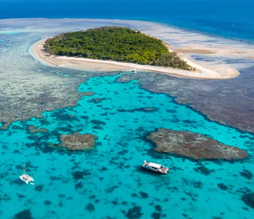 Aerial view of island with turquoise waters and coral reefs.