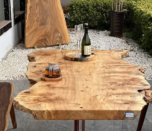 Live edge wooden table with a natural finish, set outdoors with wine and glasses.