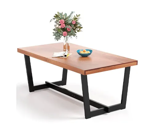 Modern wooden dining table with a black metal base, decorated with a vase of flowers and a bowl of fruit.