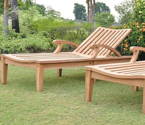 Wooden lounge chairs placed on a lawn in a garden setting.