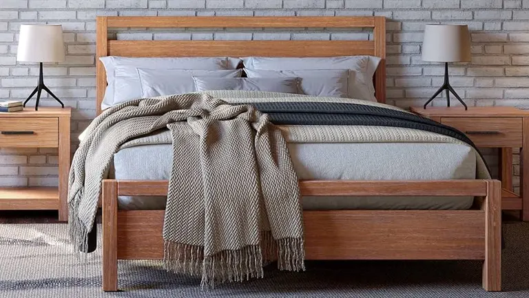 Modern wooden bed with a light finish, dressed with gray bedding and a textured beige throw blanket, flanked by matching wooden nightstands with lamps.