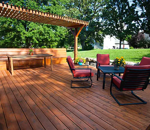 Outdoor patio setup with wooden decking, pergola, and red cushioned chairs and table