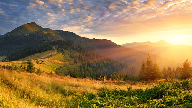 Scenic landscape with mountains, forests, and sunset.