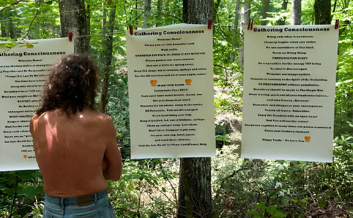 Person reading conservation guidelines posted on trees in a forest.